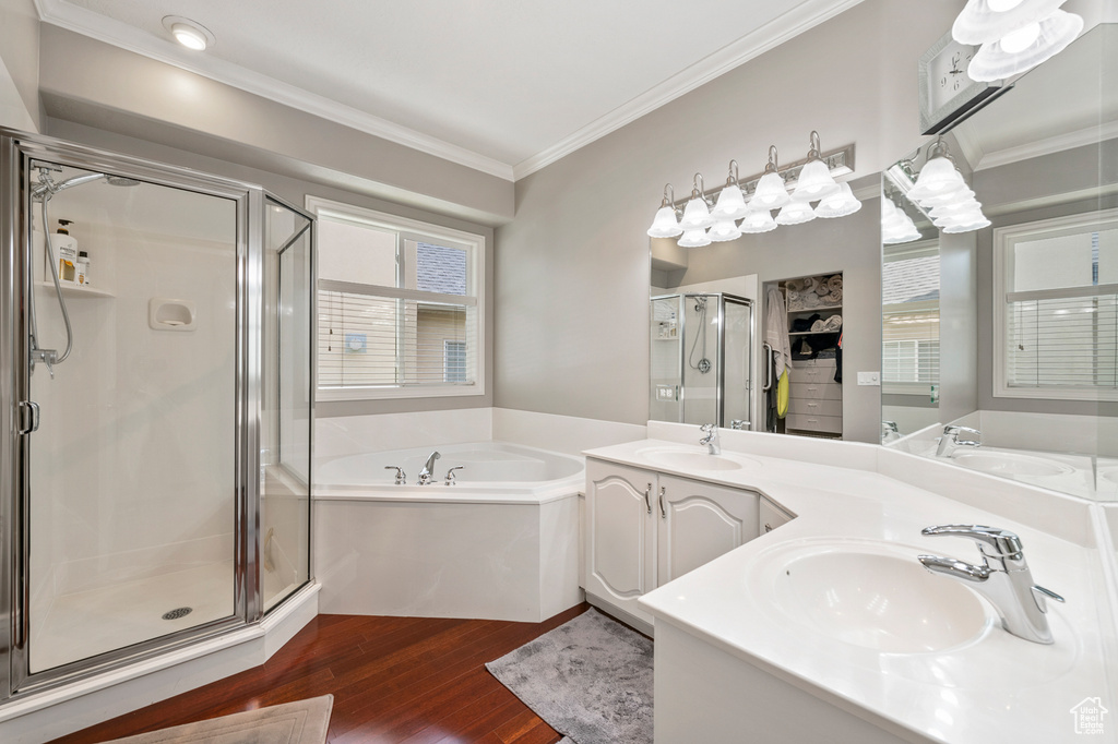 Bathroom featuring hardwood / wood-style flooring, ornamental molding, shower with separate bathtub, and dual vanity