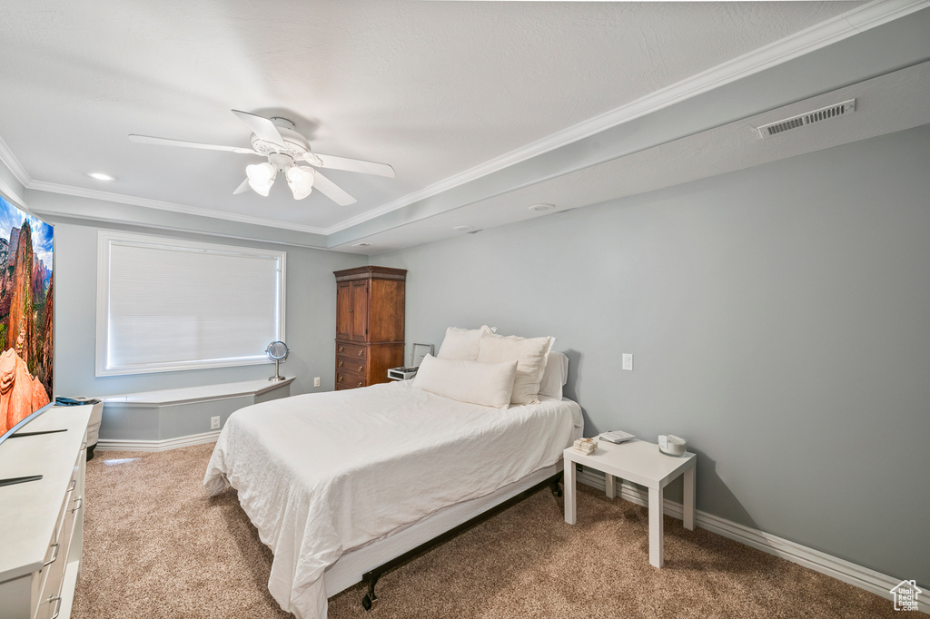 Bedroom with light colored carpet, ceiling fan, and crown molding
