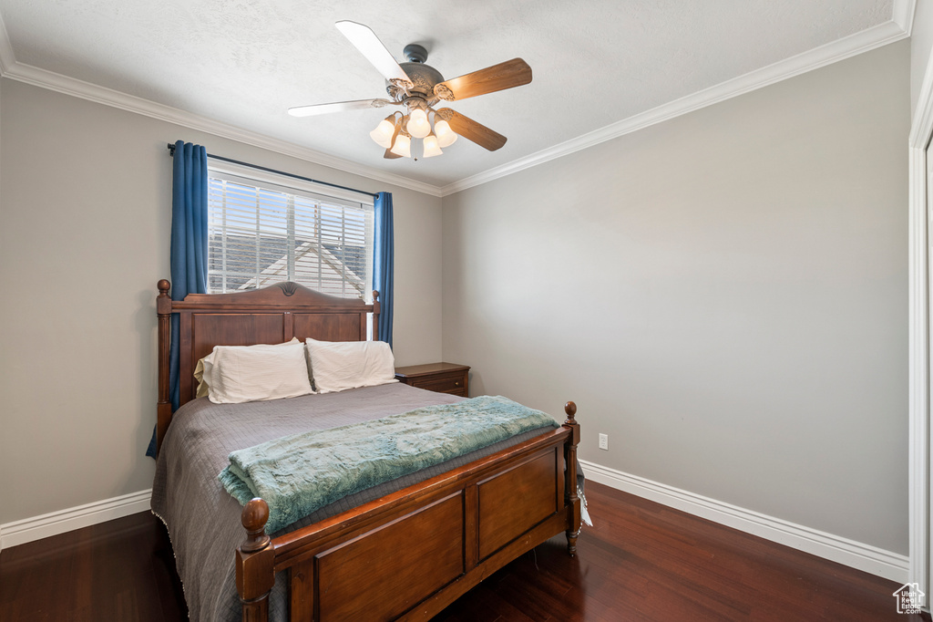 Bedroom with ceiling fan, dark wood-type flooring, and ornamental molding
