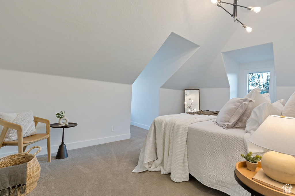 Bedroom with lofted ceiling, carpet floors, and an inviting chandelier