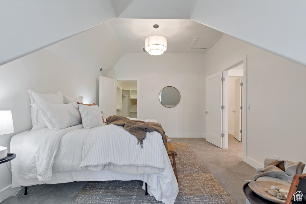 Carpeted bedroom featuring a spacious closet and vaulted ceiling