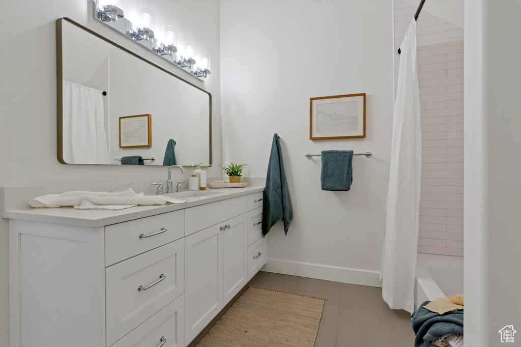 Bathroom featuring shower / bathtub combination with curtain, tile floors, and vanity