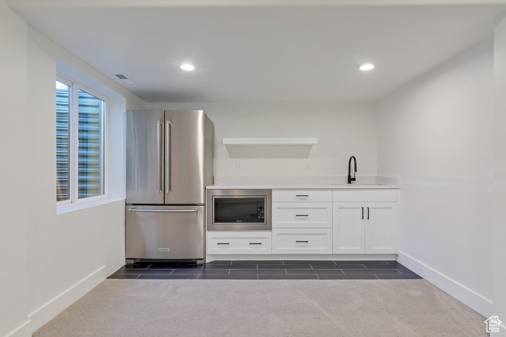 Kitchen with sink, appliances with stainless steel finishes, white cabinetry, and dark colored carpet