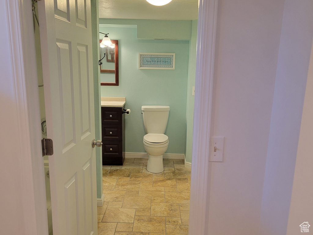 Bathroom with toilet, tile flooring, vanity, and a textured ceiling