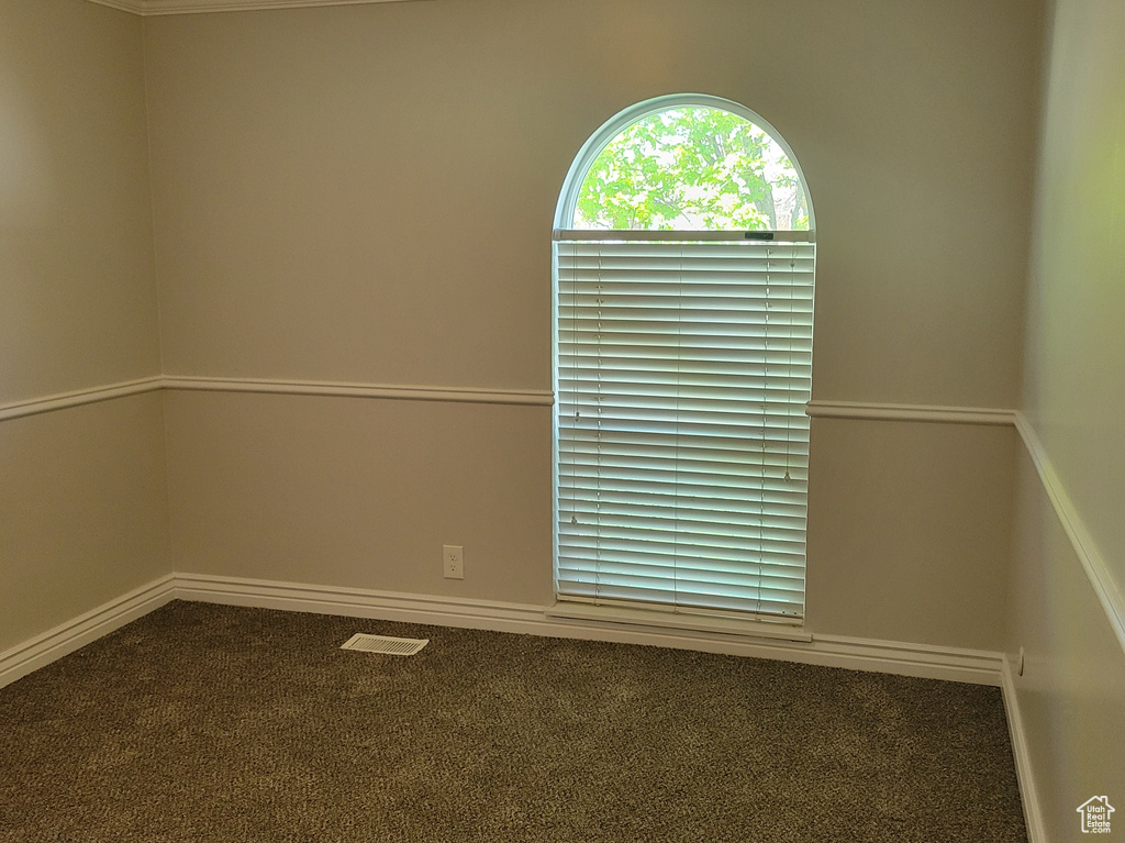 Empty room with dark carpet and crown molding