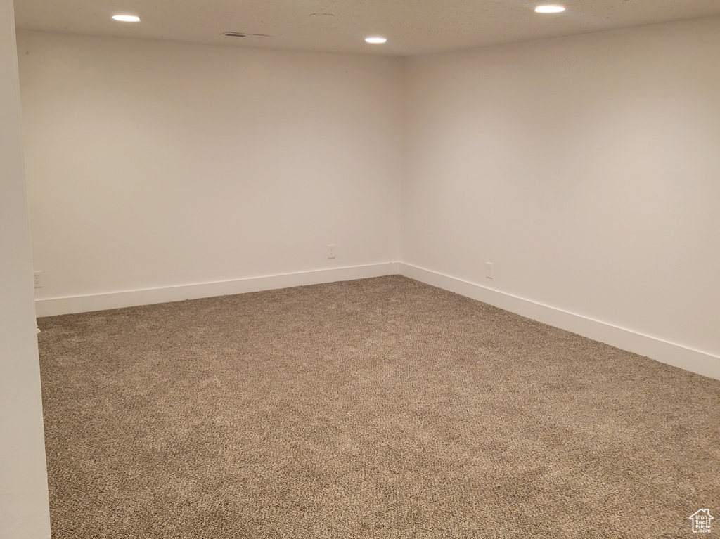 Empty room featuring dark colored carpet and a textured ceiling