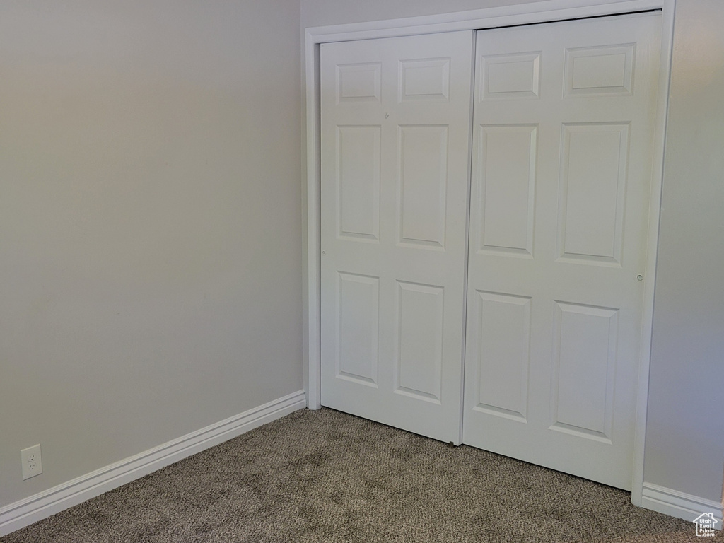 Unfurnished bedroom with a closet, ceiling fan, dark carpet, and ornamental molding