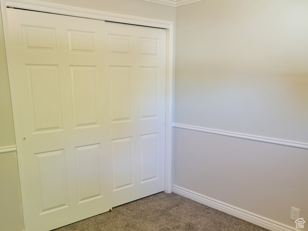 Unfurnished bedroom with a closet, dark carpet, and crown molding