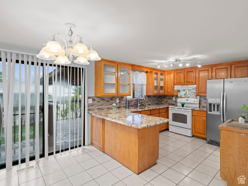 Kitchen featuring pendant lighting, kitchen peninsula, stainless steel refrigerator with ice dispenser, a notable chandelier, and white range with electric cooktop