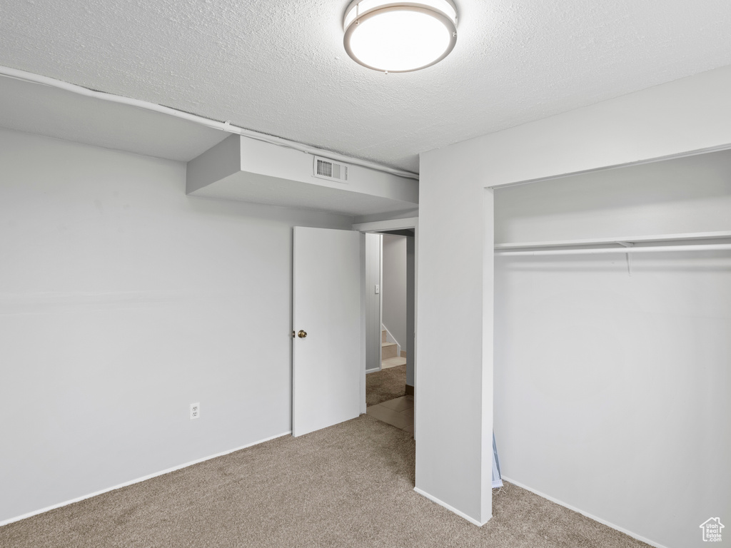 Unfurnished bedroom featuring carpet flooring, a closet, and a textured ceiling
