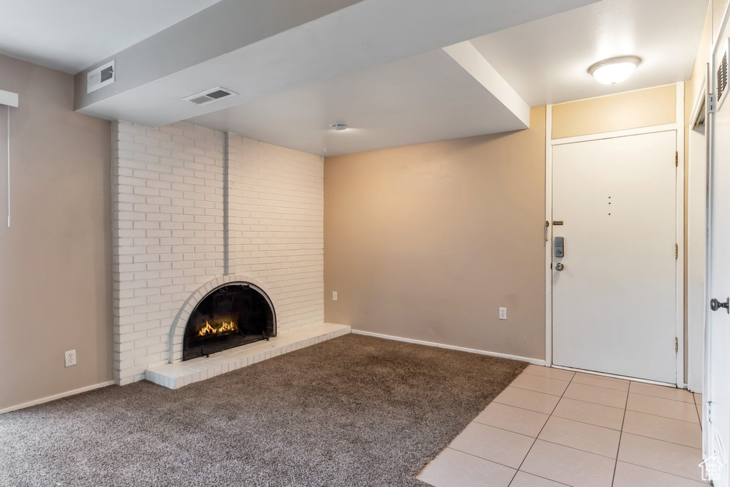 Carpeted foyer with brick wall and a brick fireplace