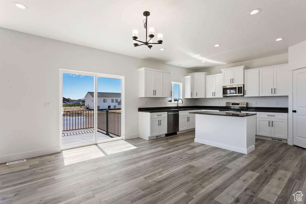Kitchen featuring pendant lighting, appliances with stainless steel finishes, light hardwood / wood-style flooring, and white cabinets