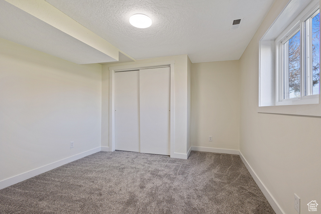 Unfurnished bedroom with a closet, a textured ceiling, and carpet flooring