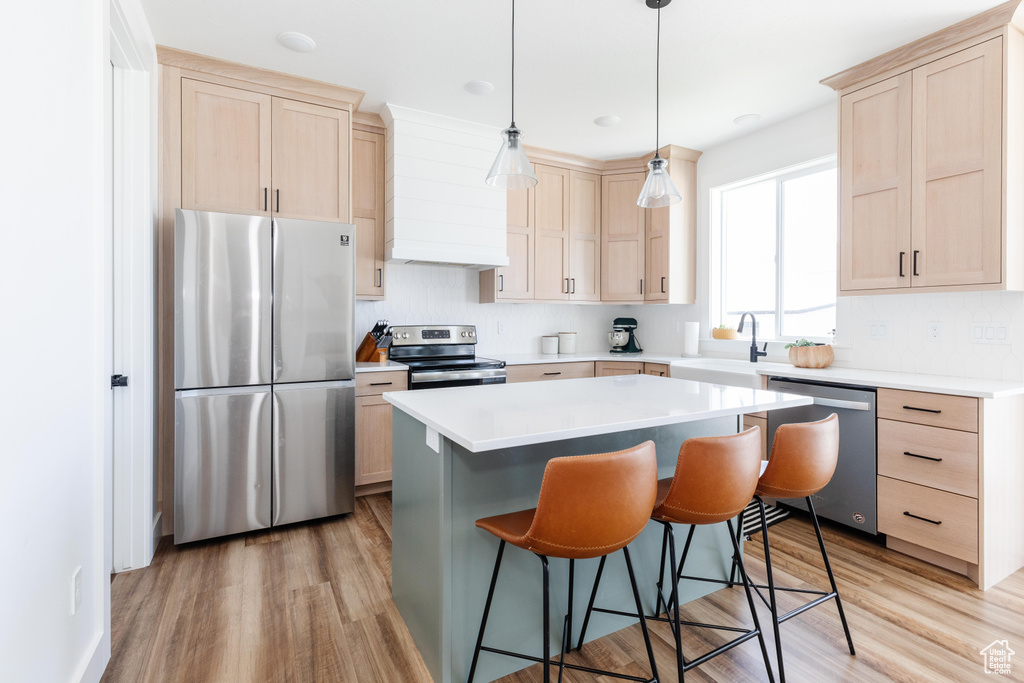 Kitchen featuring appliances with stainless steel finishes, light hardwood / wood-style flooring, sink, and a center island
