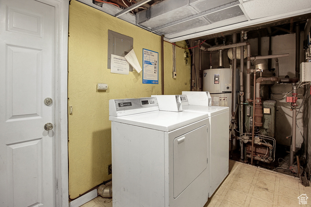 Clothes washing area featuring gas water heater, light tile floors, and washer and dryer