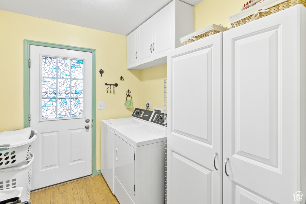 Laundry room featuring cabinets, washer and dryer, and light wood-type flooring