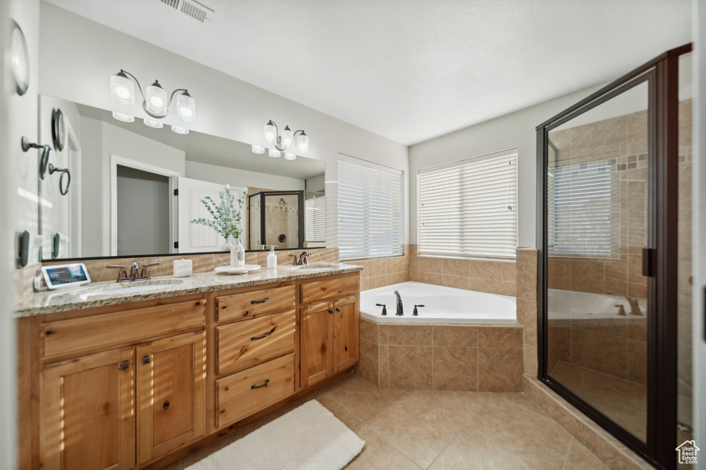 Bathroom with tile floors, double vanity, and shower with separate bathtub