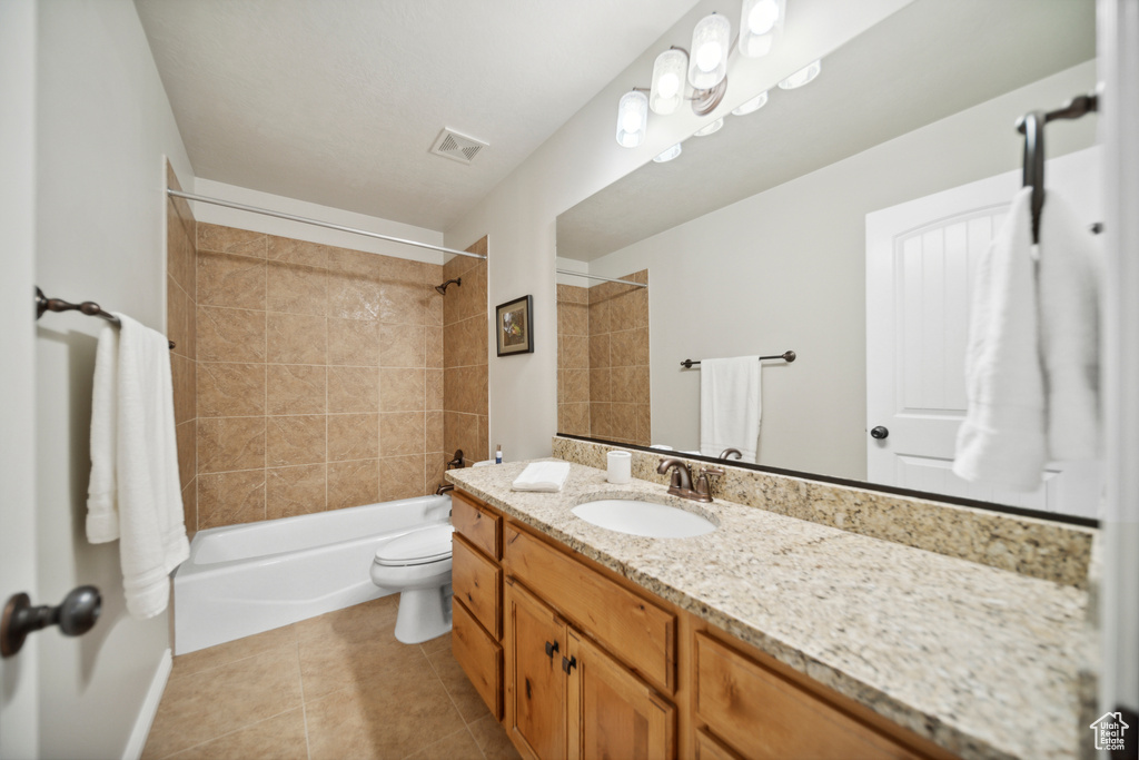 Full bathroom featuring tile floors, tiled shower / bath, vanity with extensive cabinet space, and toilet