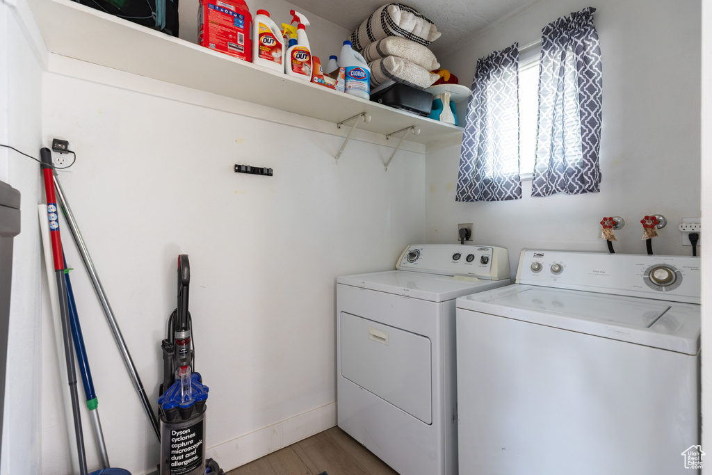 Clothes washing area with hardwood / wood-style floors, separate washer and dryer, and electric dryer hookup