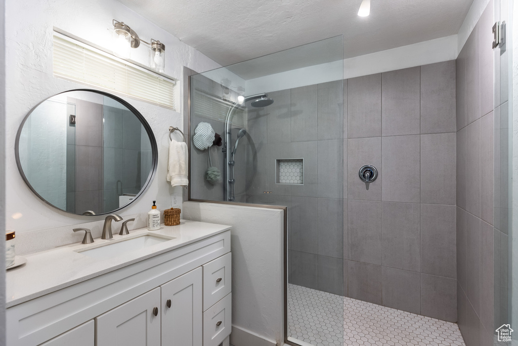 Bathroom featuring vanity with extensive cabinet space and a tile shower
