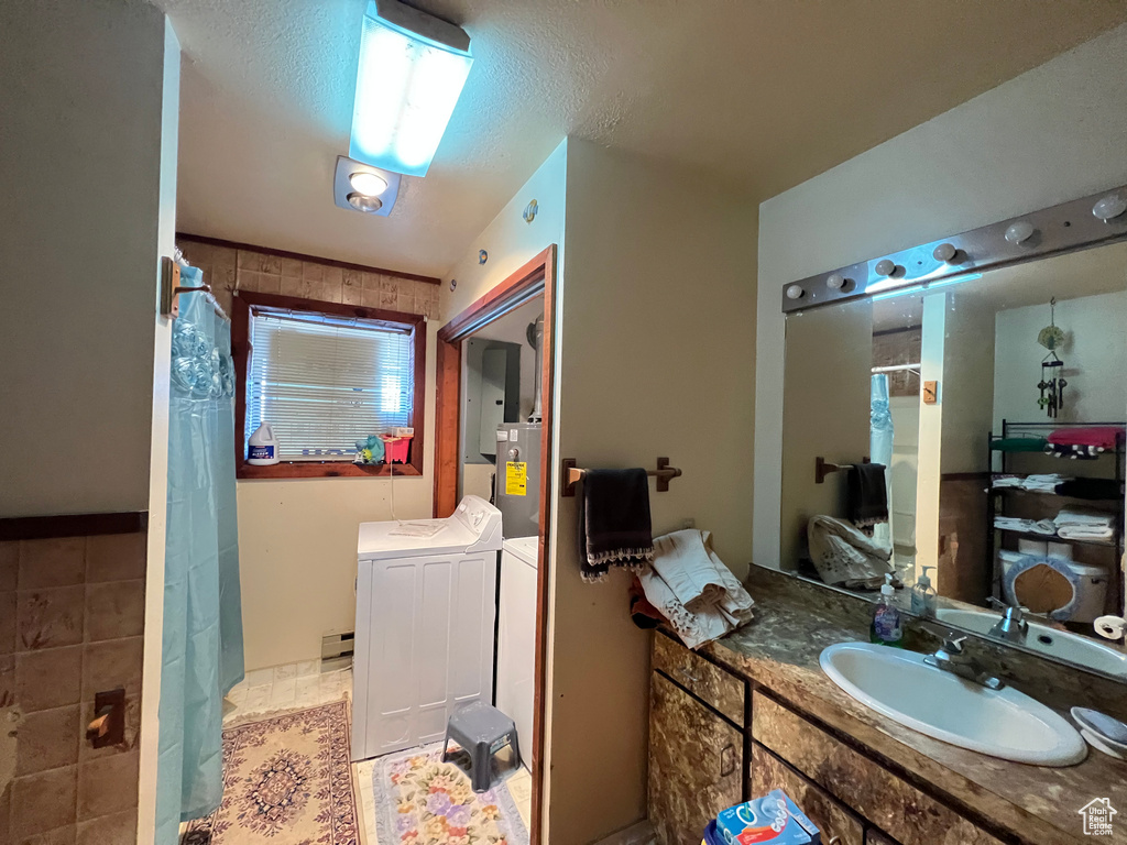 Bathroom featuring a textured ceiling, vanity, tile floors, and washer and dryer