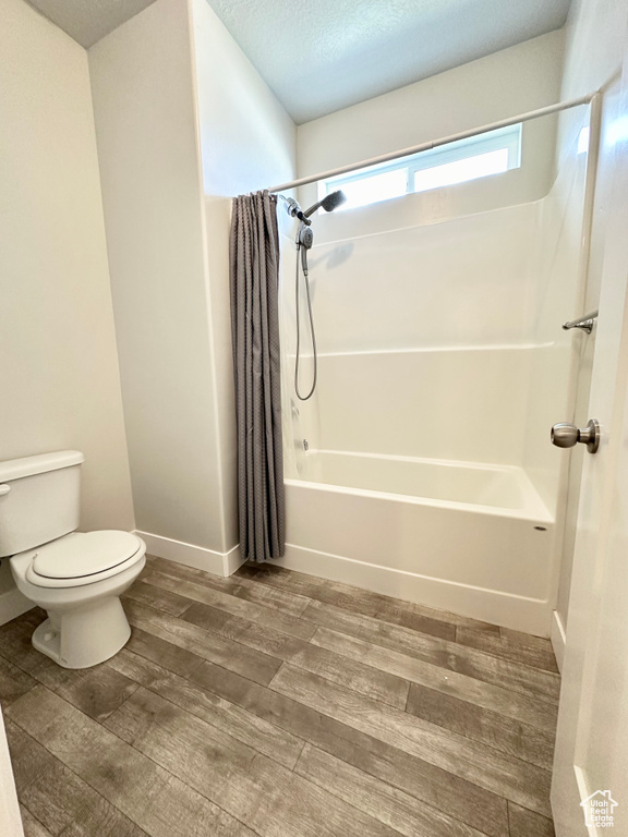 Bathroom with shower / bath combo, a textured ceiling, toilet, and hardwood / wood-style floors