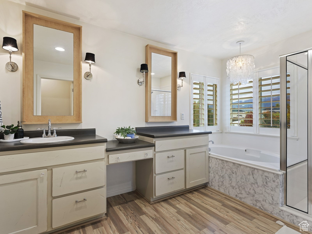 Bathroom with hardwood / wood-style floors, vanity, a chandelier, and tiled bath
