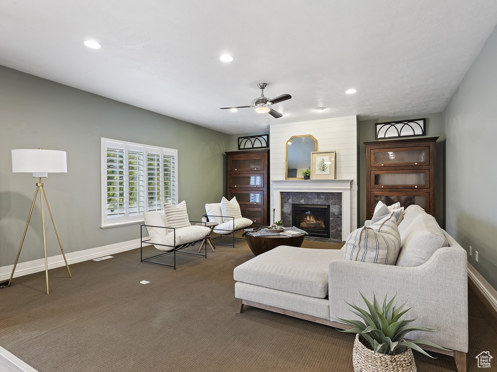 Living room with ceiling fan, a fireplace, and dark carpet