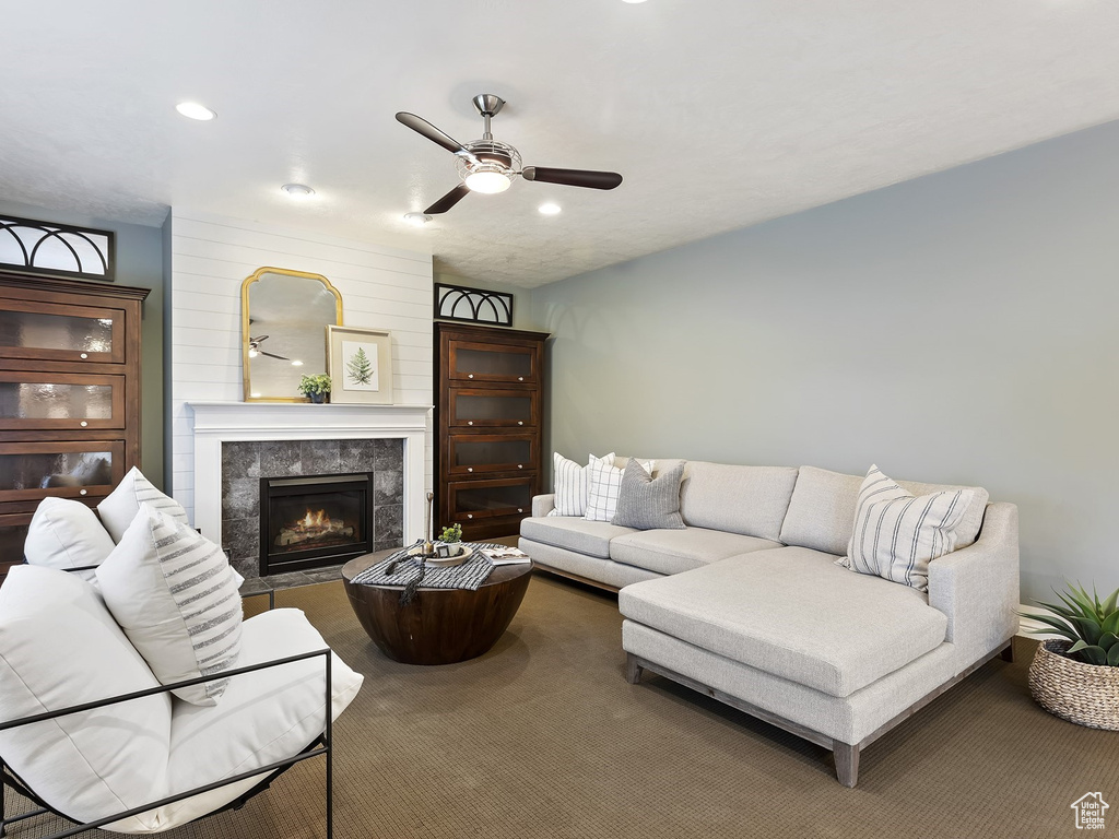 Living room featuring carpet flooring, a tile fireplace, and ceiling fan