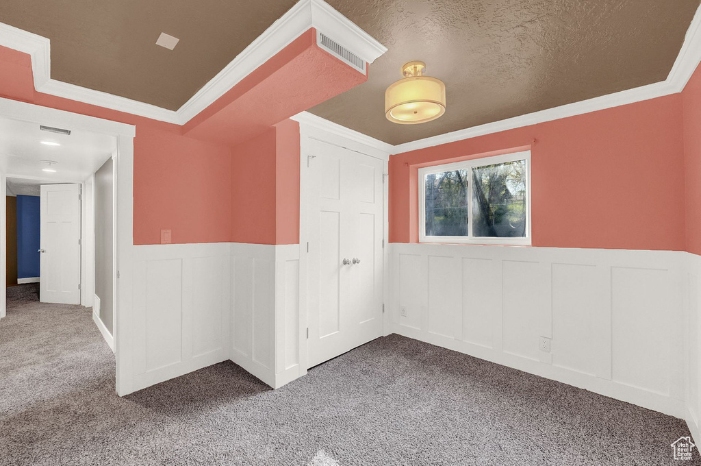 Spare room with a textured ceiling, carpet floors, and ornamental molding