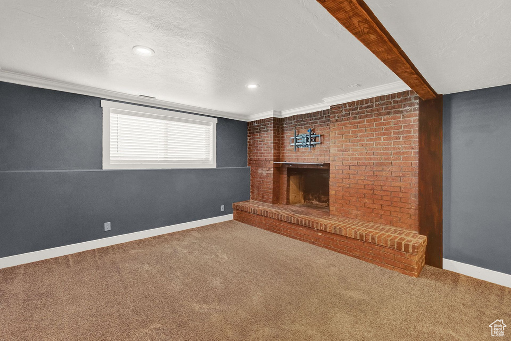 Unfurnished living room with beamed ceiling, carpet, a fireplace, and a textured ceiling