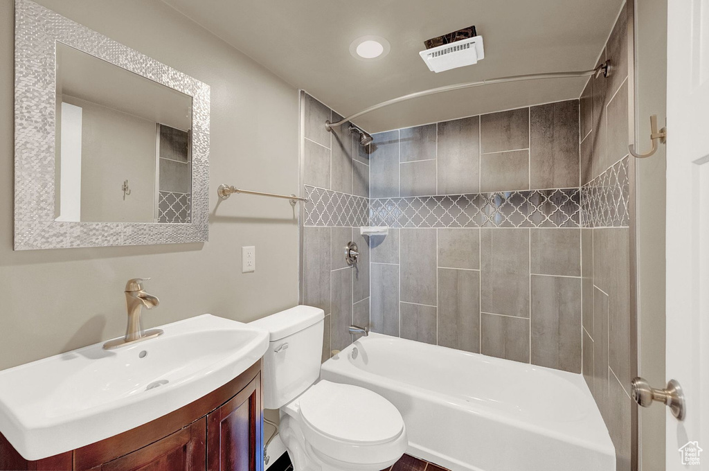 Full bathroom featuring tiled shower / bath, vanity, and toilet