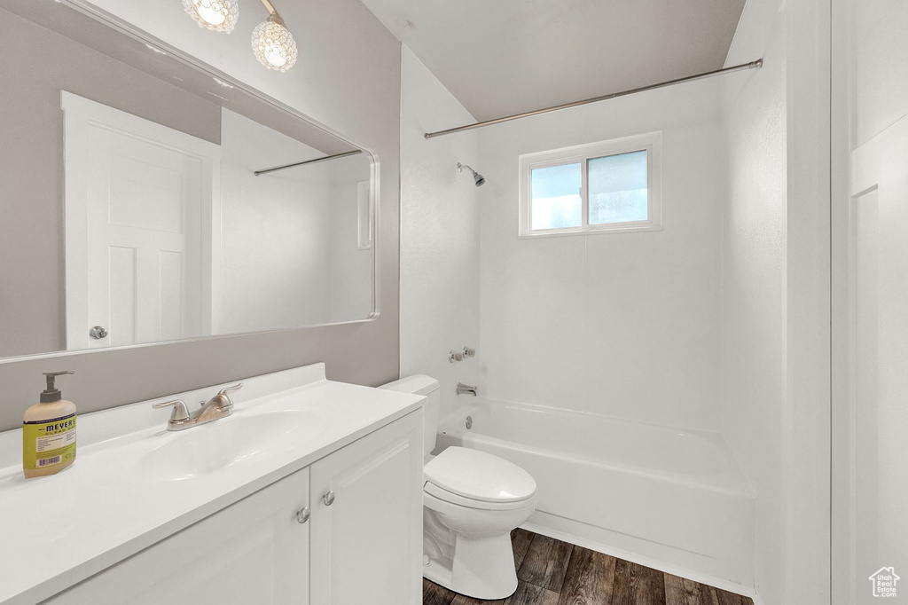 Full bathroom with washtub / shower combination, hardwood / wood-style flooring, vanity, and toilet