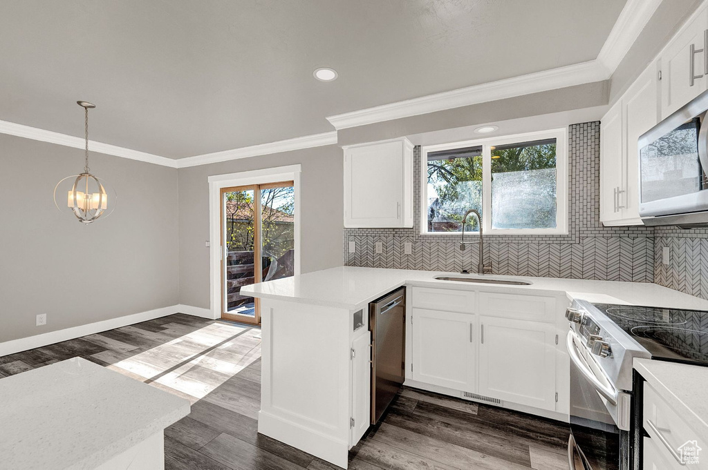 Kitchen with decorative light fixtures, white cabinets, white appliances, dark hardwood / wood-style floors, and kitchen peninsula