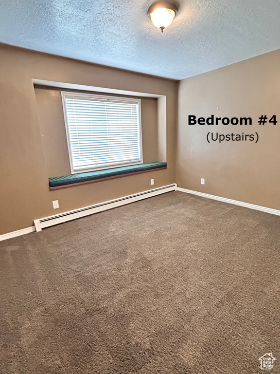 Carpeted spare room featuring a textured ceiling and a baseboard heating unit