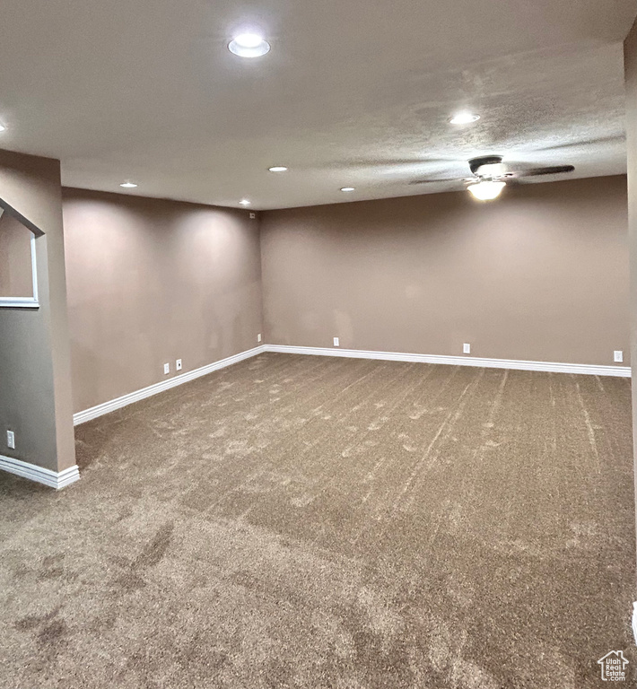 Basement featuring a textured ceiling, ceiling fan, and carpet flooring