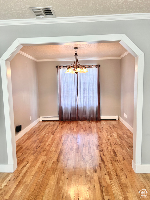 Unfurnished room featuring a chandelier, crown molding, a textured ceiling, and hardwood / wood-style floors