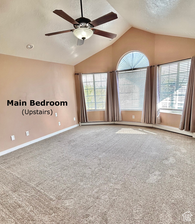 Carpeted empty room with a wealth of natural light, ceiling fan, and vaulted ceiling