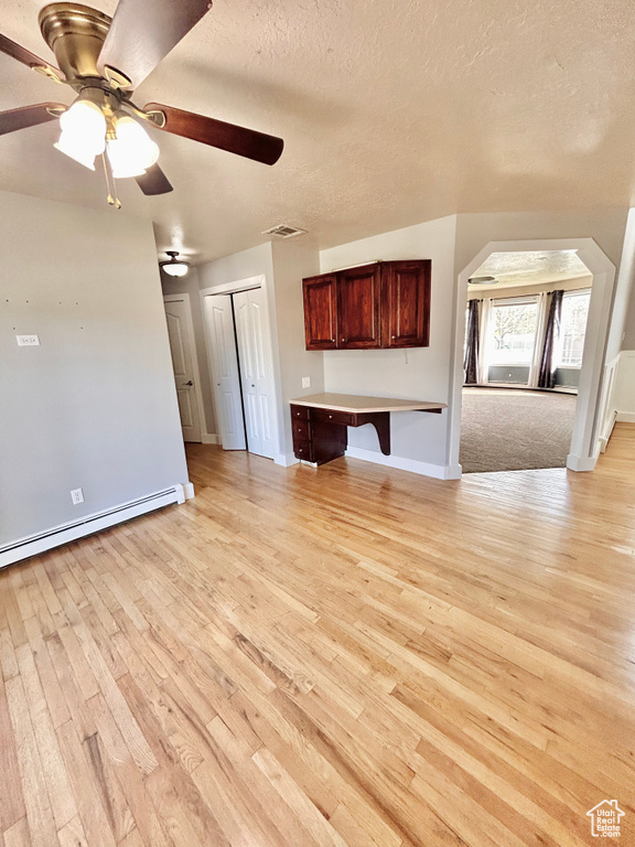 Unfurnished living room featuring light hardwood / wood-style floors, ceiling fan, and baseboard heating