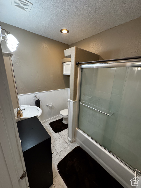 Bathroom with a textured ceiling, vanity, toilet, and tile flooring