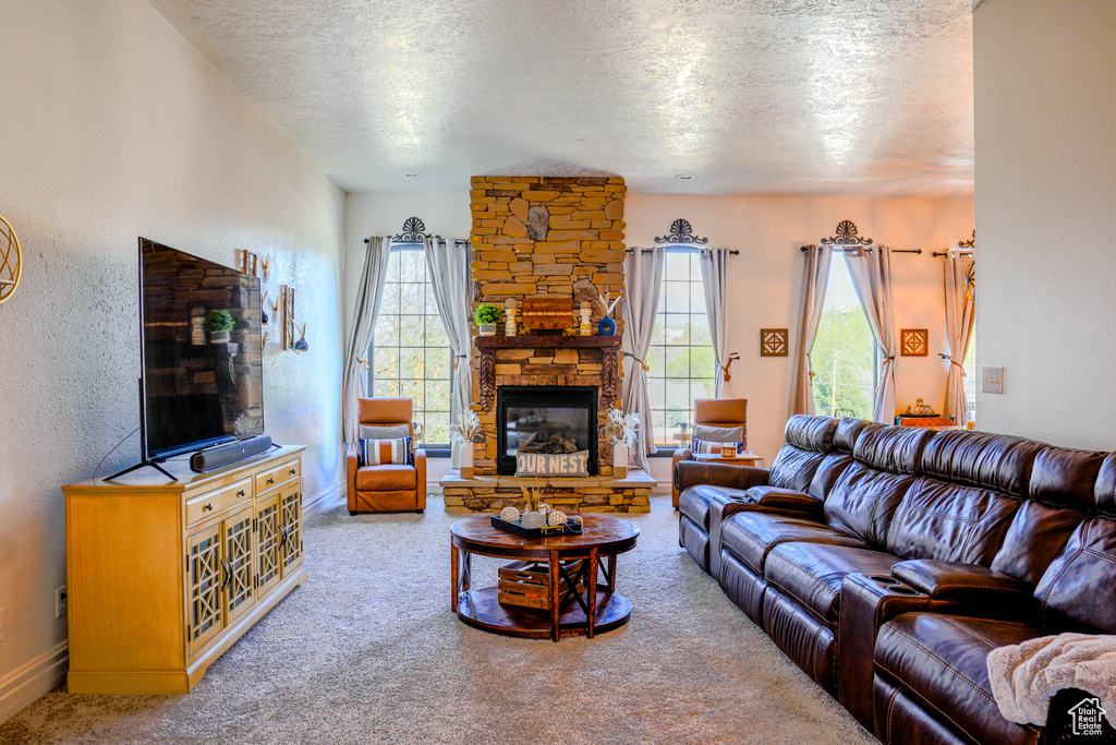 Living room with a stone fireplace, carpet flooring, and a textured ceiling