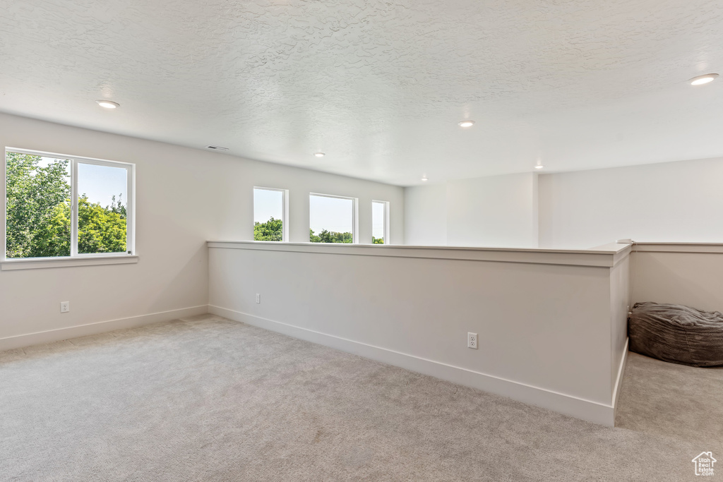 Carpeted spare room with plenty of natural light and a textured ceiling
