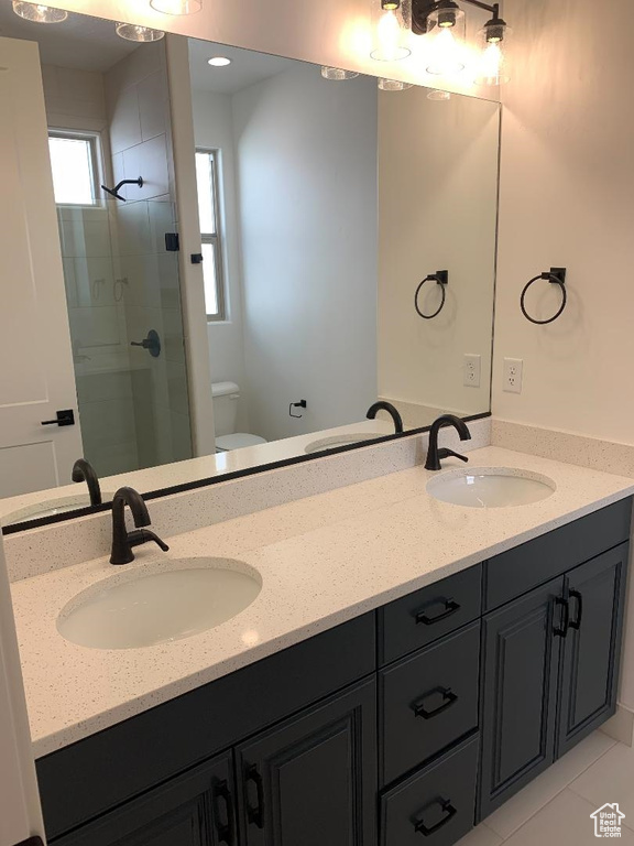 Bathroom featuring walk in shower, tile flooring, toilet, and double vanity