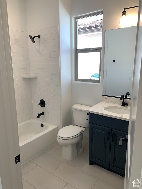 Full bathroom with toilet, tile flooring, tiled shower / bath combo, and vanity