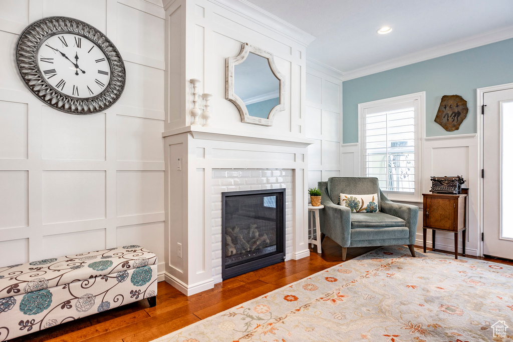 Sitting room featuring dark hardwood / wood-style floors, ornamental molding, and a brick fireplace