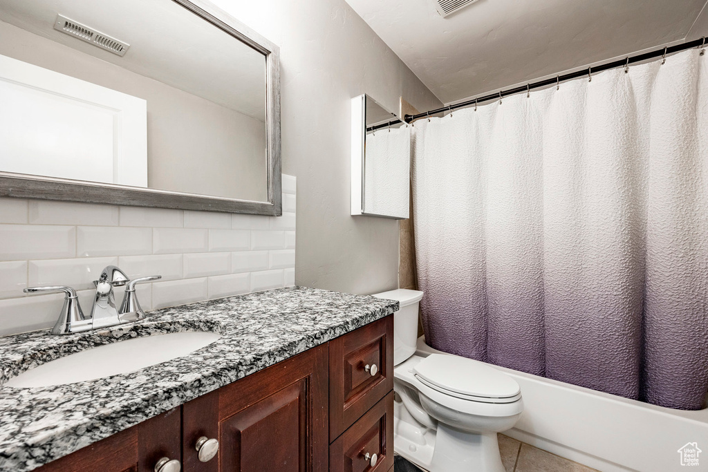 Full bathroom with tile walls, backsplash, toilet, shower / bath combo with shower curtain, and vanity