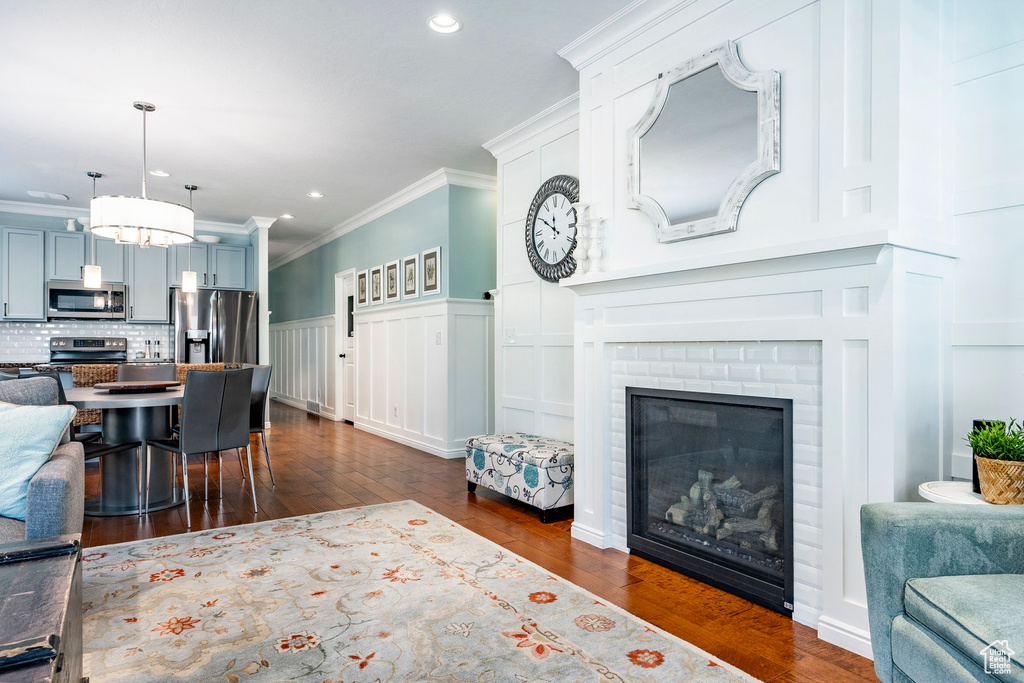 Living room with ornamental molding, dark hardwood / wood-style flooring, and a brick fireplace