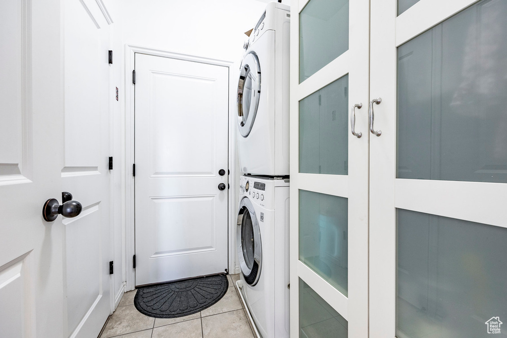 Laundry room featuring stacked washer / dryer and light tile flooring