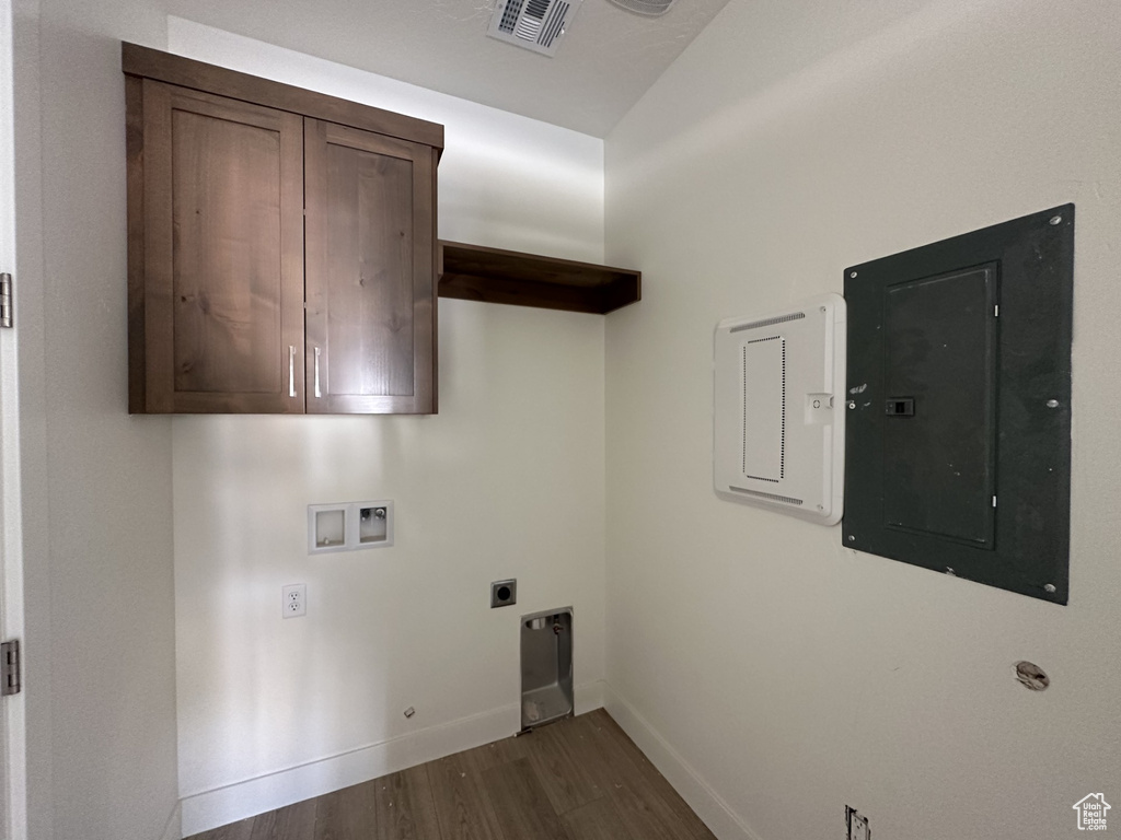 Clothes washing area with washer hookup, electric panel, cabinets, and dark hardwood / wood-style flooring