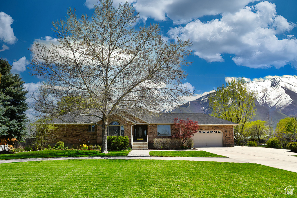 View of front of home featuring a garage, a mountain view, and a front yard